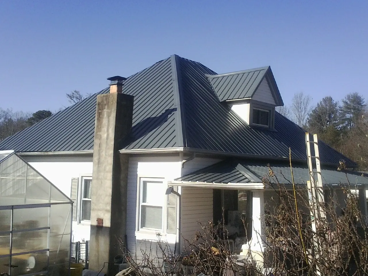 Dark blue standing seam metal roof on a white farmhouse with dormer — Slate & Tile Roof Repair by Roofing Brothers in Boothbay Harbor