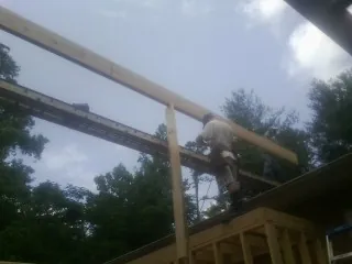 Carpenter setting a ridge beam over a new addition frame — Ice Dam Removal by Roofing Brothers in Boothbay Harbor