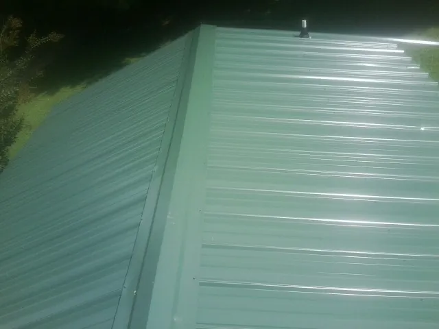 New green metal panels meeting at the ridge of a roof — Flat Roof Repair work by our crew in Boothbay Harbor