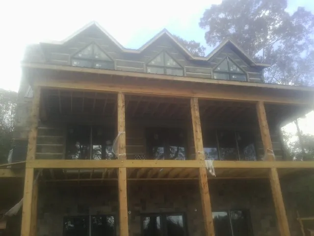 Dormers and porch framing on a large log home under construction — Roof Coating work by our crew in Boothbay Harbor