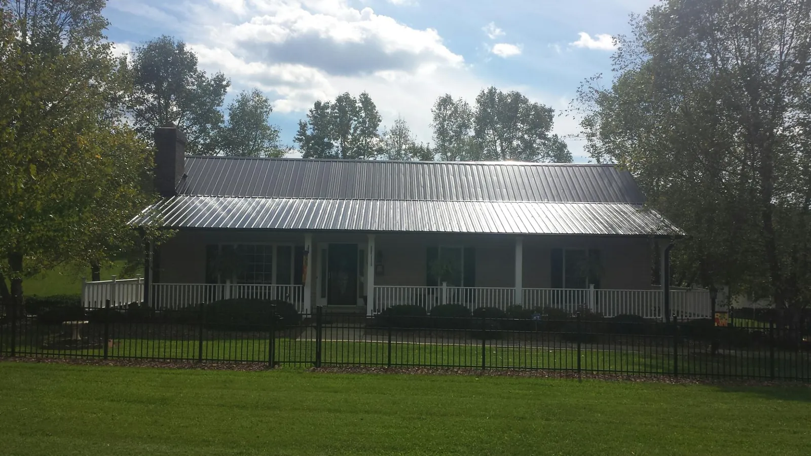 Gray metal roof on a brick ranch with a full width front porch — Gutter Guard Installation work by our crew in Boothbay Harbor