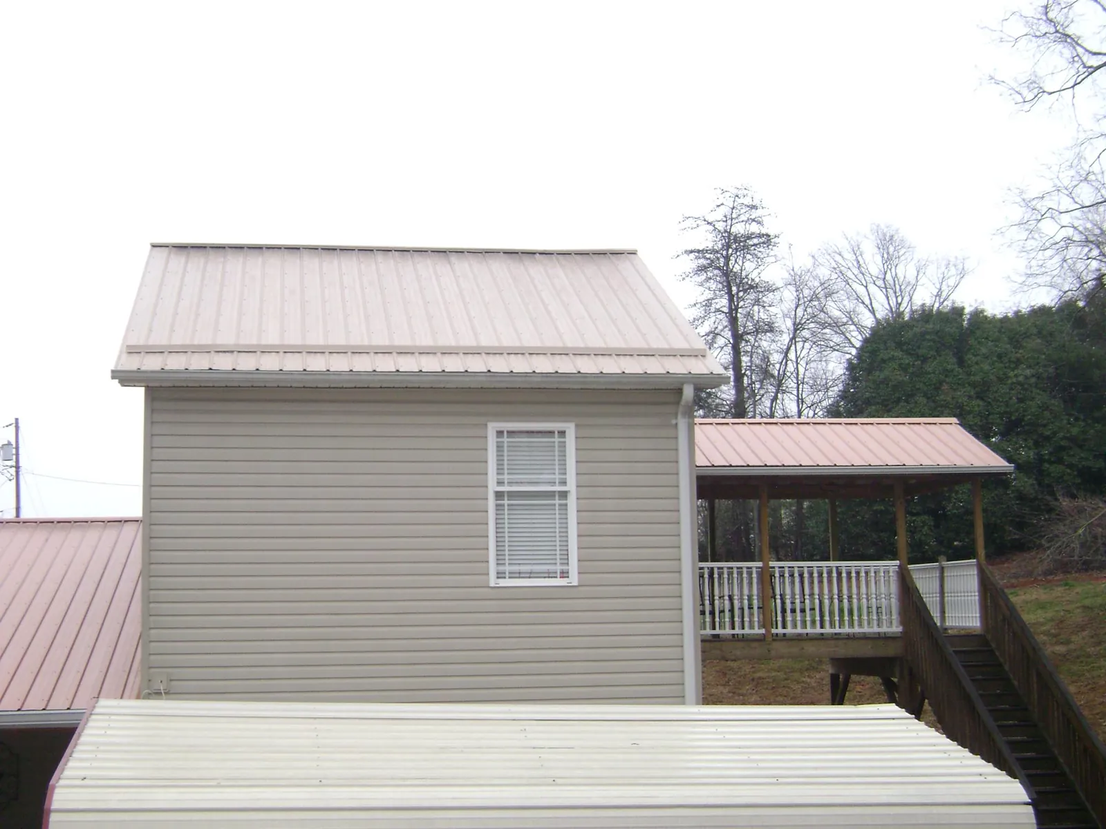 Tan metal roofs on a two story addition and attached porch, from a Roof Replacement job in Boothbay Harbor